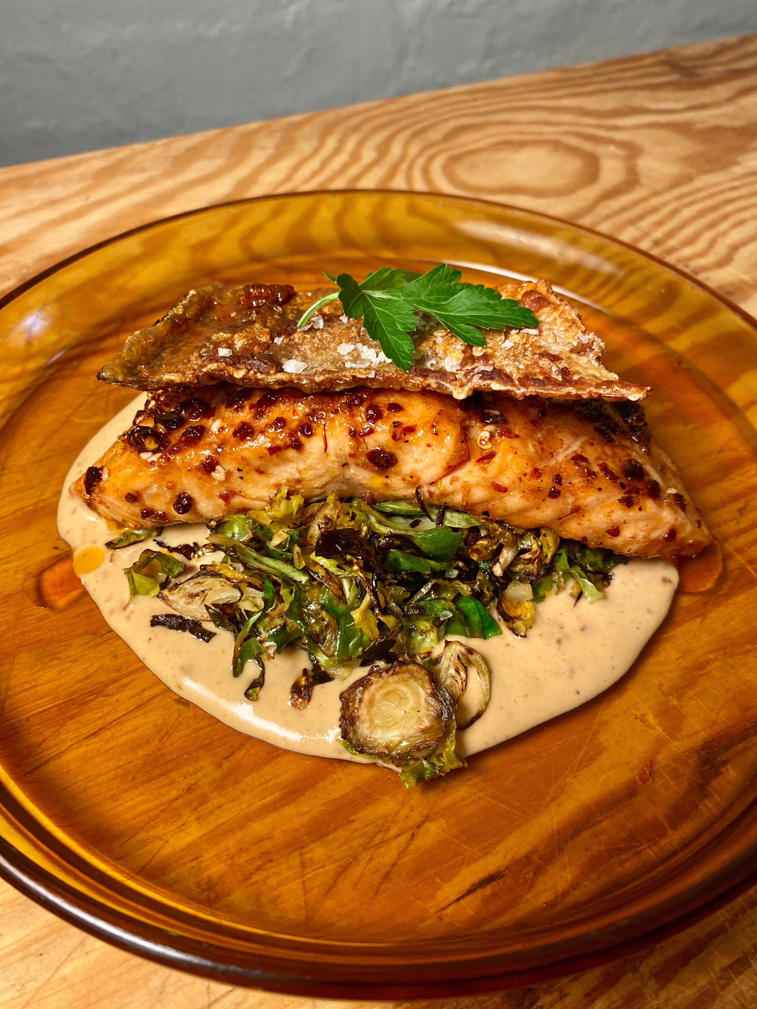 a plate of crispy salmon with charred brussels sprouts and umami tahini